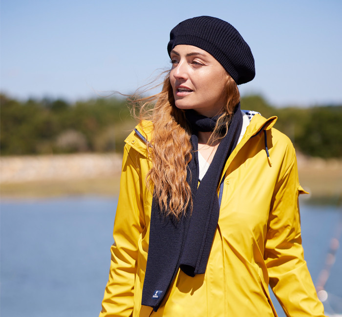 Femme portant un ciré jaune avec un bonnet et une écharpe