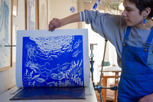 Morgane Chouin en train de décoller le papier imprimé du motif de sa linogravure Mousqueton