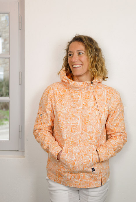 Femme portant une veste en toile Mousqueton à motifs oranges, avec une fermeture asymétrique.