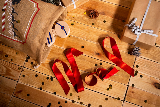 Noël écrit en ruban rouge entouré de cadeaux et logo Mousqueton