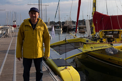 Charlie Capelle devant son bateau jaune portant une veste Baden jaune