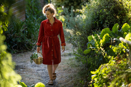 Une femme portant une robe en velours avec un panier de légumes d'automne
