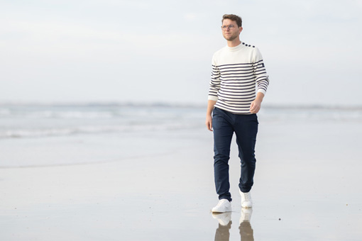 Un homme en pull Mousqueton au bord de l'eau