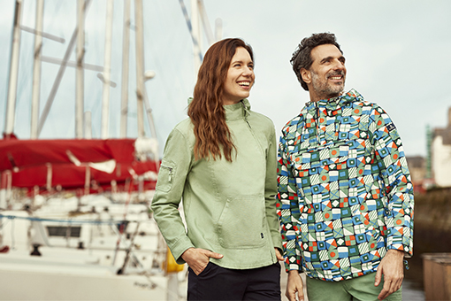 two people wearing a green mid-season vest and a nautical flag printed pea jacket