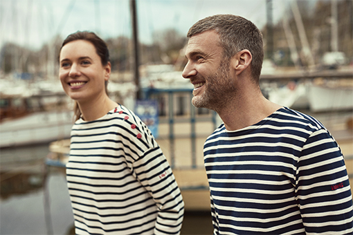 A men wearing a blue and white breton shirt and a women wearing a ecru and blue sailor's striped shirt