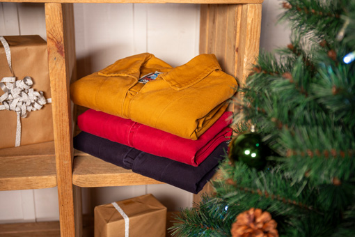 Pile de vareuses Cachou Mousqueton entourée d'un sapin et d'un cadeau de Noël