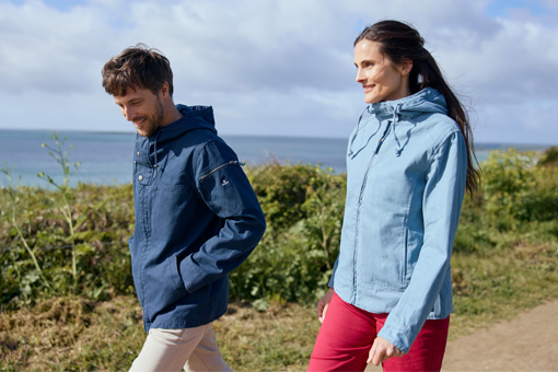 Un homme et une femme se promenant au bord de mer avec leurs vestes en toile Mousqueton